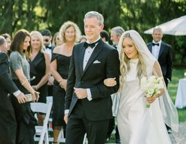 Father of the bride in black tuxedo walking his daughter down the aisle