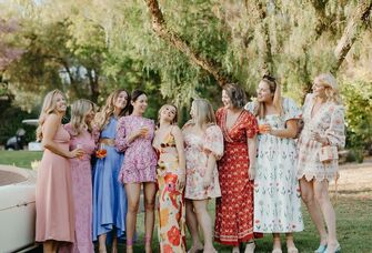 bride stands with guests in coordinating outfits at wedding welcome party