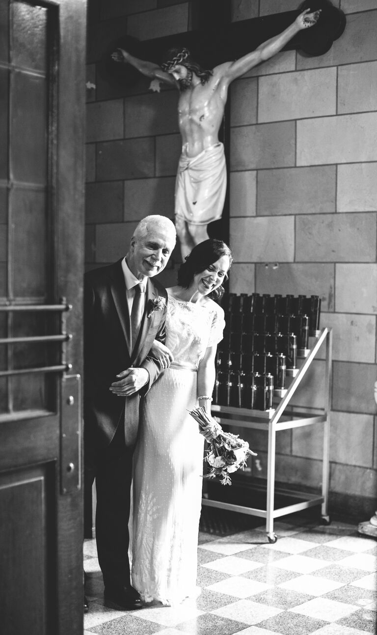 A bride and her father peeking down the ceremony aisle before the wedding
