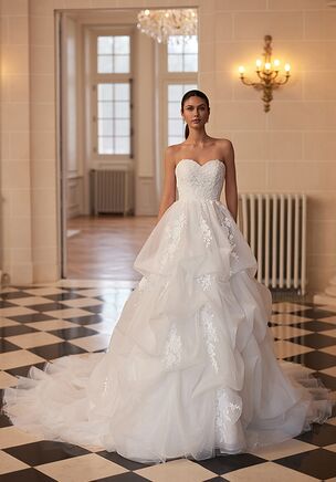 The Moonlight Couture H1654 wedding dress is a regal A-line gown featuring a strapless sweetheart bodice adorned with shimmering lace appliqués and a flattering drop waist that flows into a voluminous skirt with billowy pickups. Crafted in layers of net and organza and finished with a dramatic chapel train, this ivory gown delivers timeless, princess-worthy elegance for the most formal celebrations.