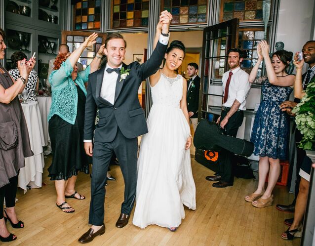 Bride and groom entrance at wedding reception with guests cheering