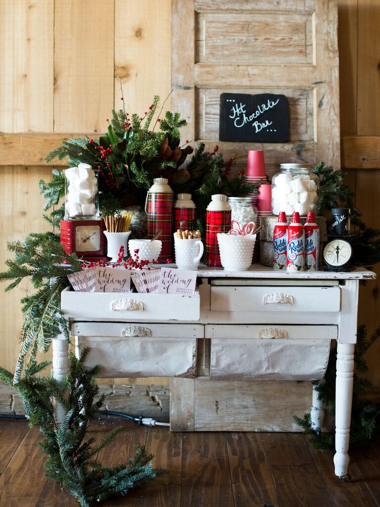 DIY hot chocolate bar on vintage dresser with greenery, chalkboard sign and red plaid thermoses 