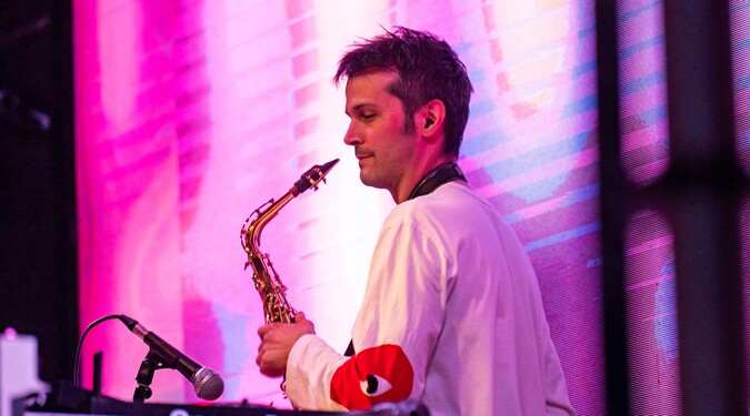 Tim Lacatena playing a saxophone on stage.