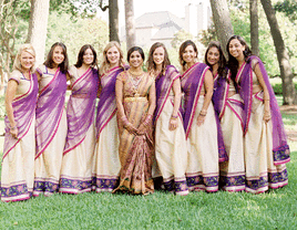 Bride and bridesmaid photo shoot wearing purple, green, and gold wedding saris. 