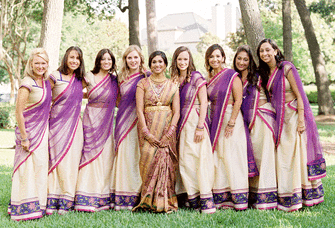 Bride and bridesmaid photo shoot wearing purple, green, and gold wedding saris. 