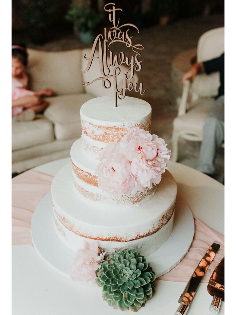 Semi-naked rustic wedding cake with white icing and pastel peonies with succulents