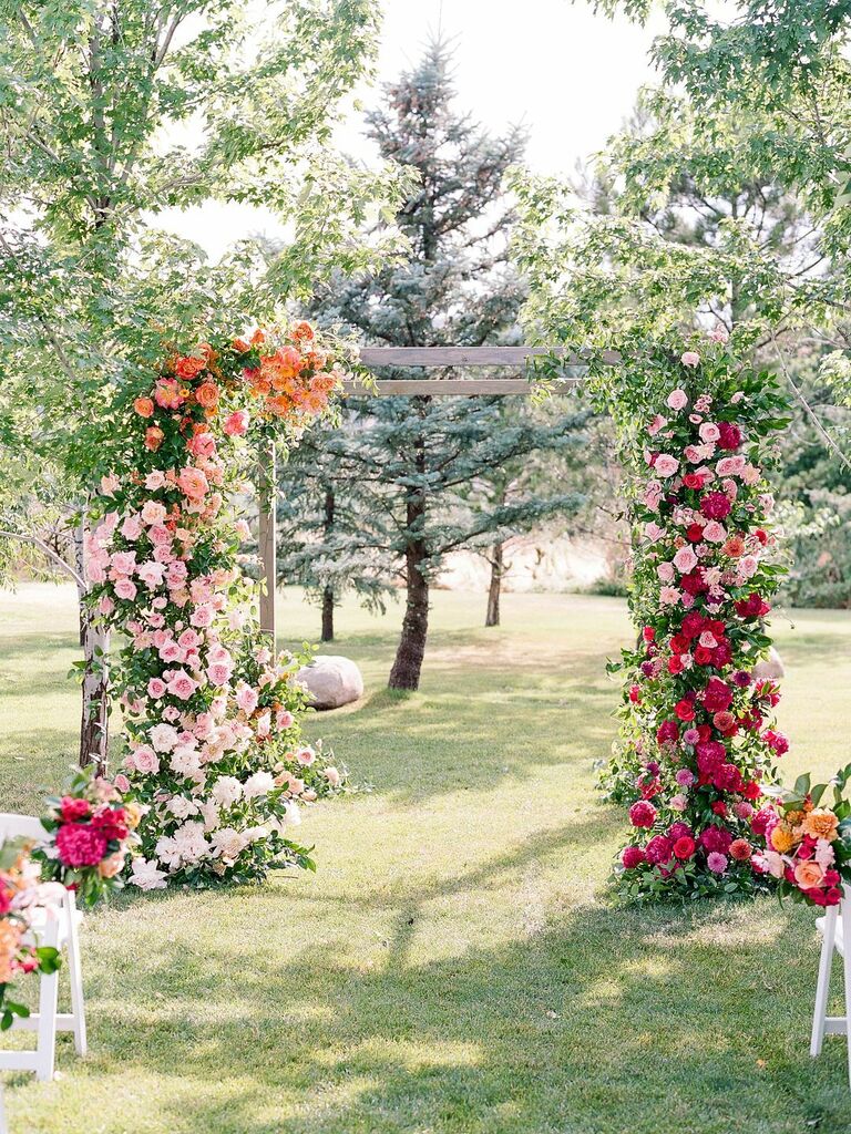 Wood arch covered in rainbow-hued fresh flowers