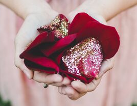 Bridesmaid holding glitter-covered red rose petals