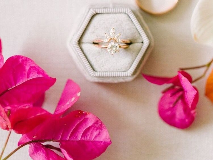 A wedding engagement ring in ring box styled beside fresh bougainvillea flowers