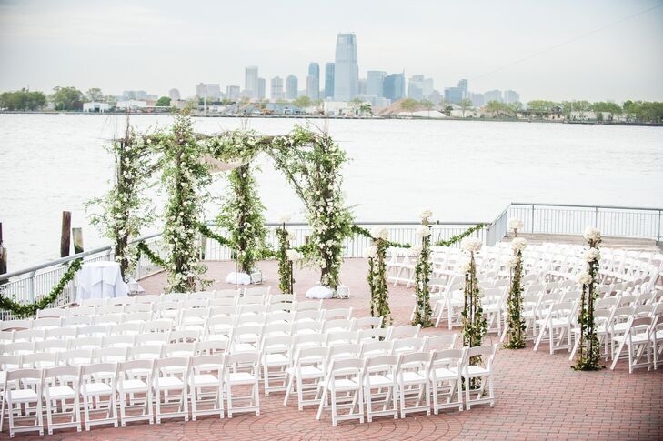 Greenery chuppah at waterfront patio with skyline views in the background. 