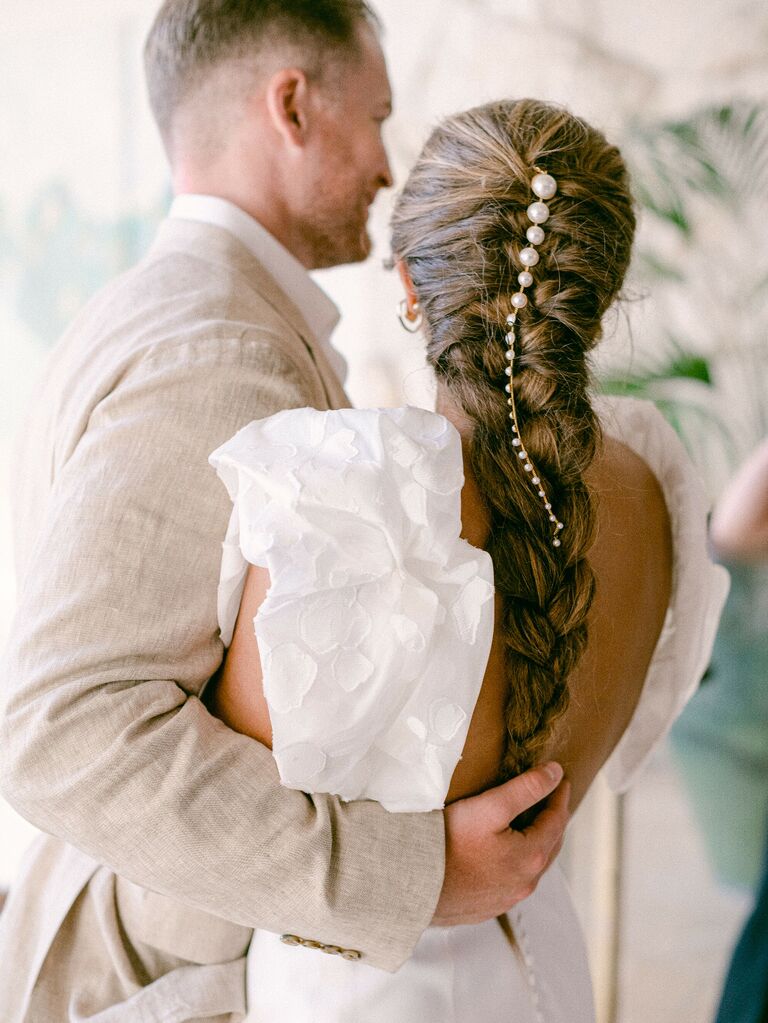 Bride wearing ruffled dress with pearls in long braid