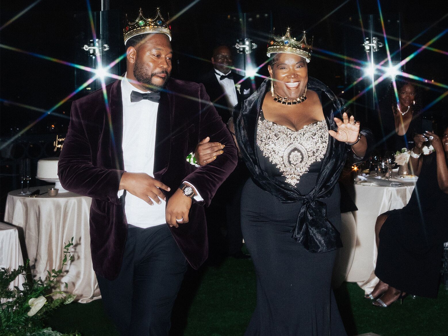 Groom and his mother wearing crowns at wedding reception