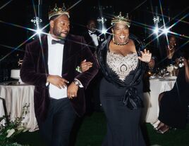 Groom and his mother wearing crowns at wedding reception