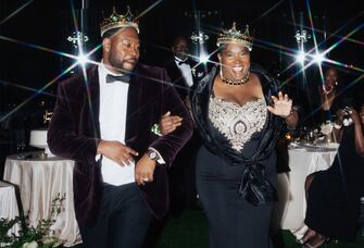 Groom and his mother wearing crowns at wedding reception