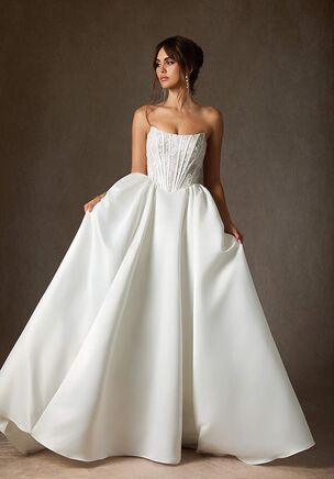 The Mirabeth ball gown is a modern, sleek lace and satin style featuring a scoop neckline, exposed boning at the bodice, a basque waist, and a voluminous pleated skirt with a chapel-length train.