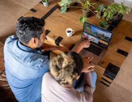 Happy couple at home booking a trip online