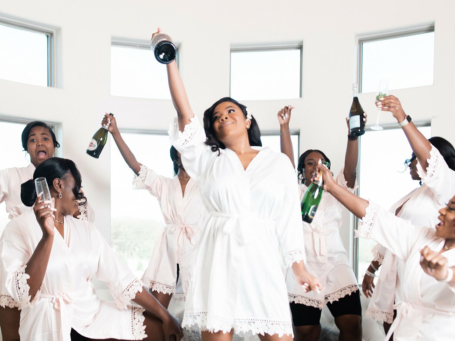 bride and bridesmaids wearing robes and celebrating with champagne