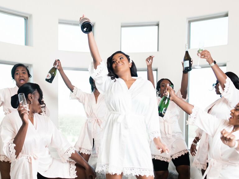 bride and bridesmaids wearing robes and celebrating with champagne