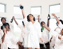 bride and bridesmaids wearing robes and celebrating with champagne