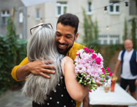 Son-in-law hugging mother-in-law with flowers