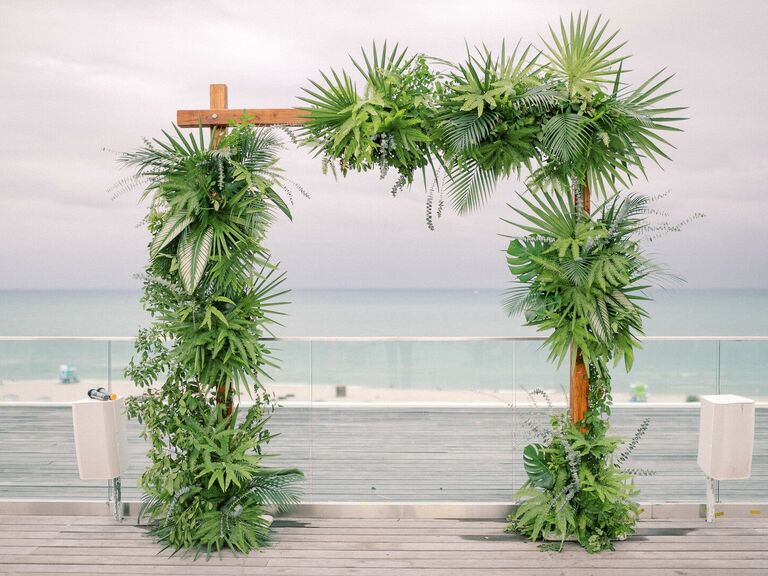 Square wedding arch covered with lush greenery. 