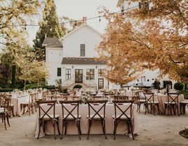 Outdoor reception space beside a charming white house venue and surrounded by trees