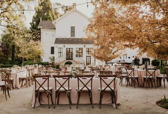 Outdoor reception space beside a charming white house venue and surrounded by trees