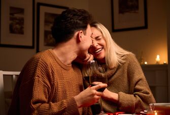 Couple laughing together while drinking a glass of wine