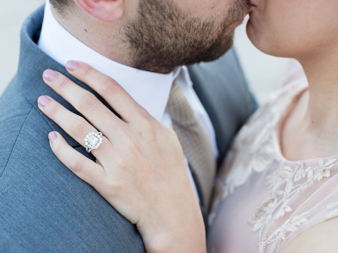 Couple kissing while woman showing off her engagement ring