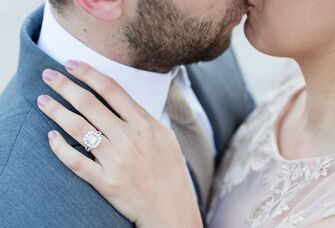 Couple kissing while woman showing off her engagement ring