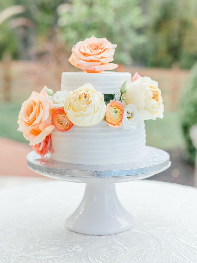 two tier wedding cake with textured buttercream and pastel pink and yellow roses