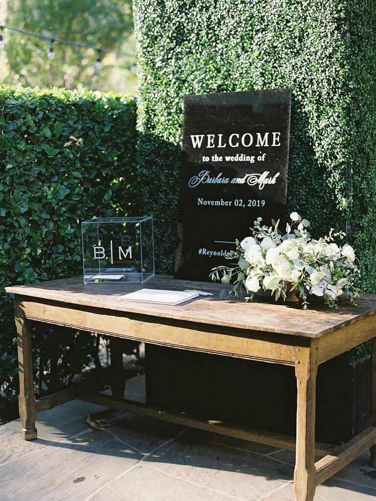minimalist wedding gift table with black acrylic welcome sign, acrylic card box and white rose centerpiece