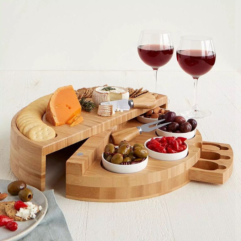 Swiveling cheese board adorned with cheeses, crackers, and olives. 