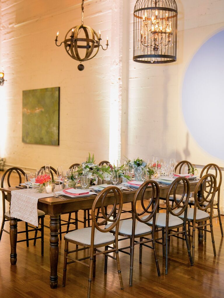 classic indoor wedding reception with long banquet table and wooden infinity chairs