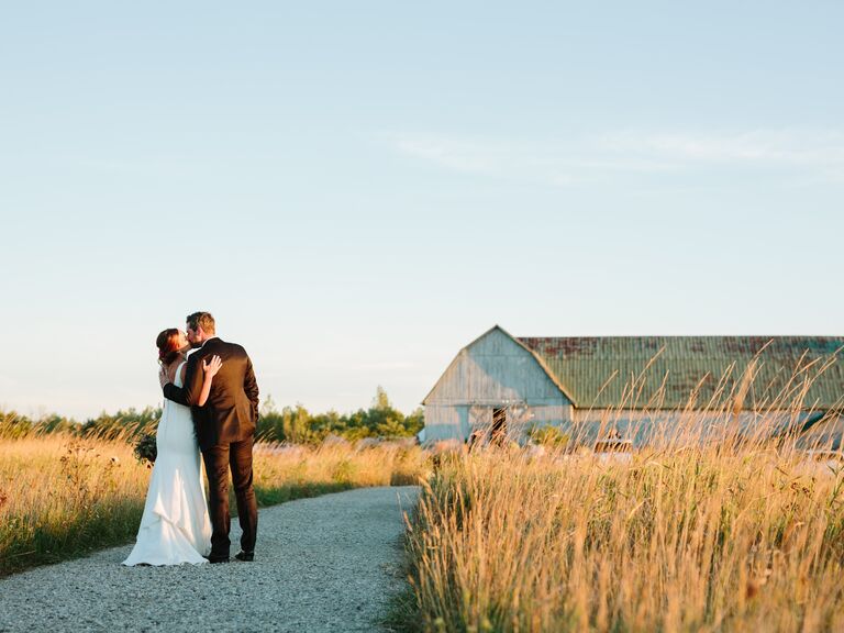 Couple portrait outside the barn venue surrounded by fields