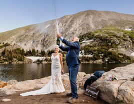 Married couple popping champagne by a lake