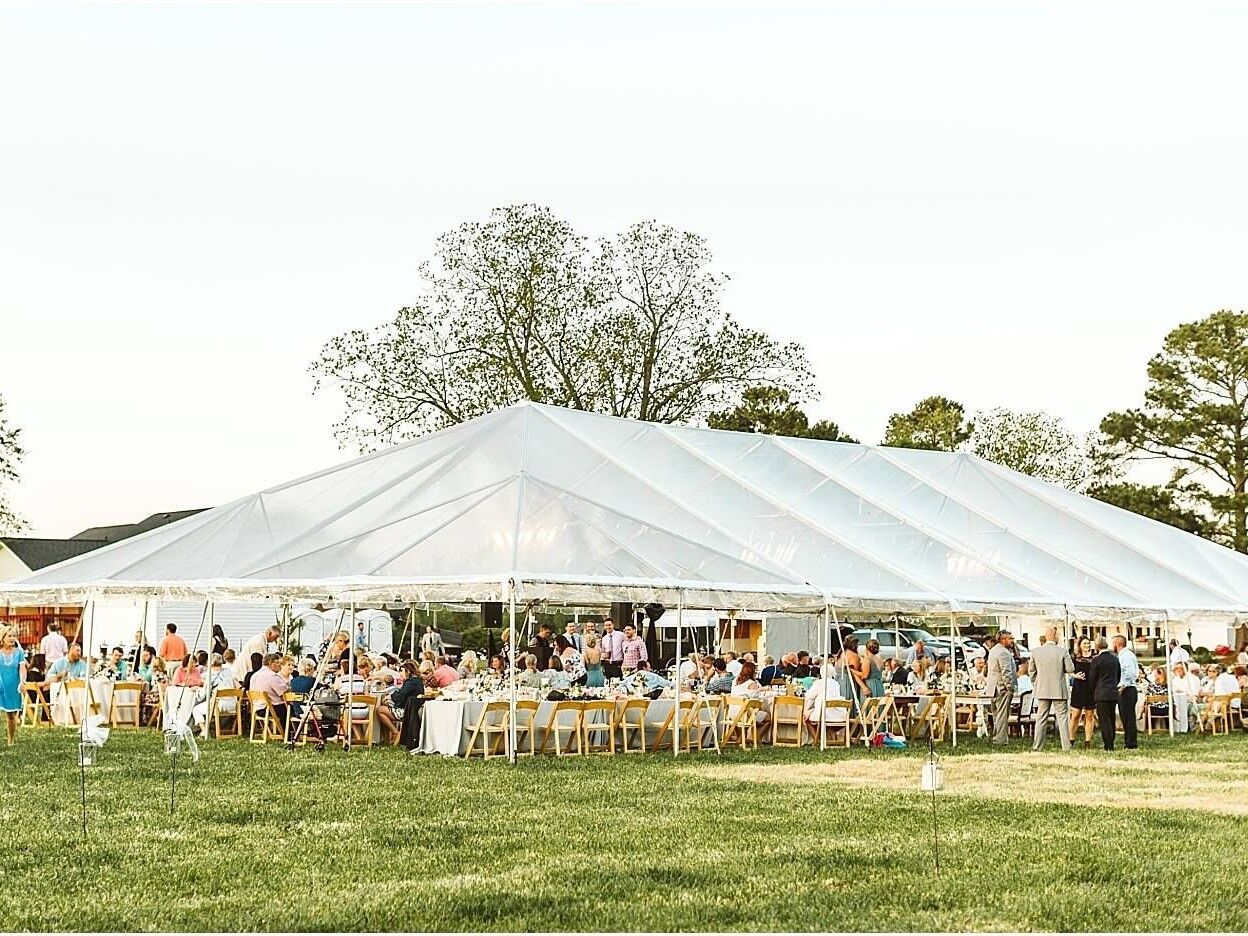 Outdoor wedding reception inside an open-air event tent