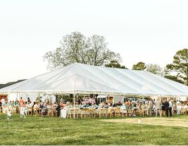 Outdoor wedding reception inside an open-air event tent