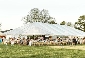 Outdoor wedding reception inside an open-air event tent