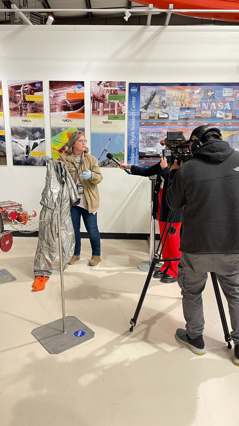 Renee displays the MC-2 pressure suit worn by Neil Armstrong to the L28 news crew at the museum.
