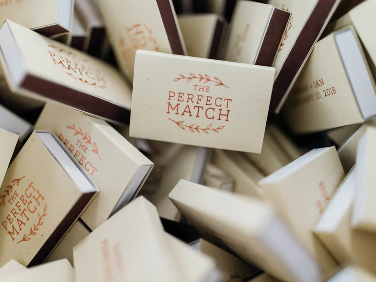 Bulk wedding matchboxes that say "The Perfect Match" surrounded by a leaf arch