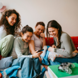 Group of women on couch looking at phone, best bachelorette party planning apps