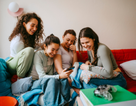 Group of women on couch looking at phone, best bachelorette party planning apps