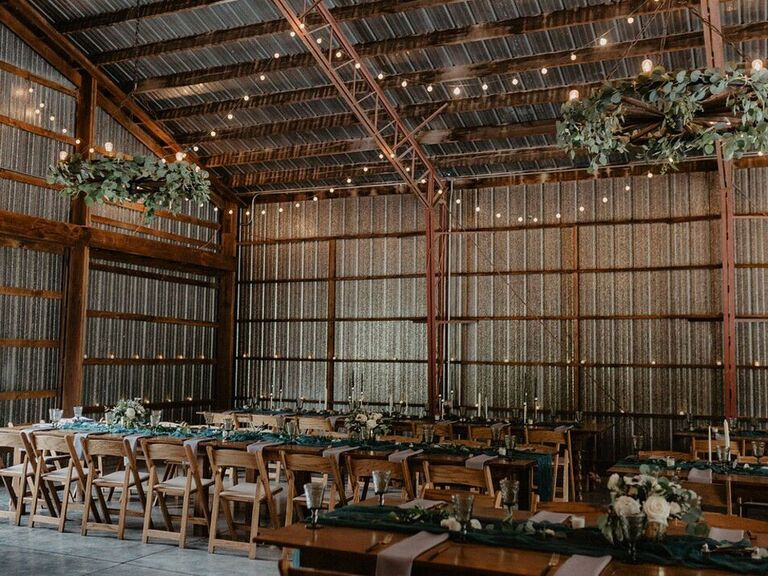 Industrial barn wedding reception with hanging greenery wreaths