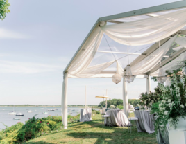 Outdoor reception venue with white tent on the water