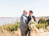 LGBTQ+ couple embracing on rustic lakeside overlook