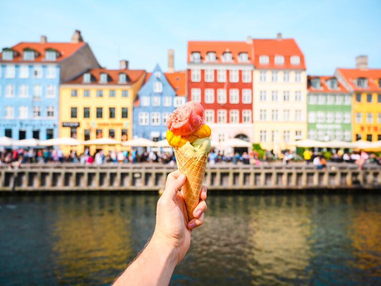 Personal perspective of tourist holding an ice cream in front of Nyhavn canal, Copenhagen