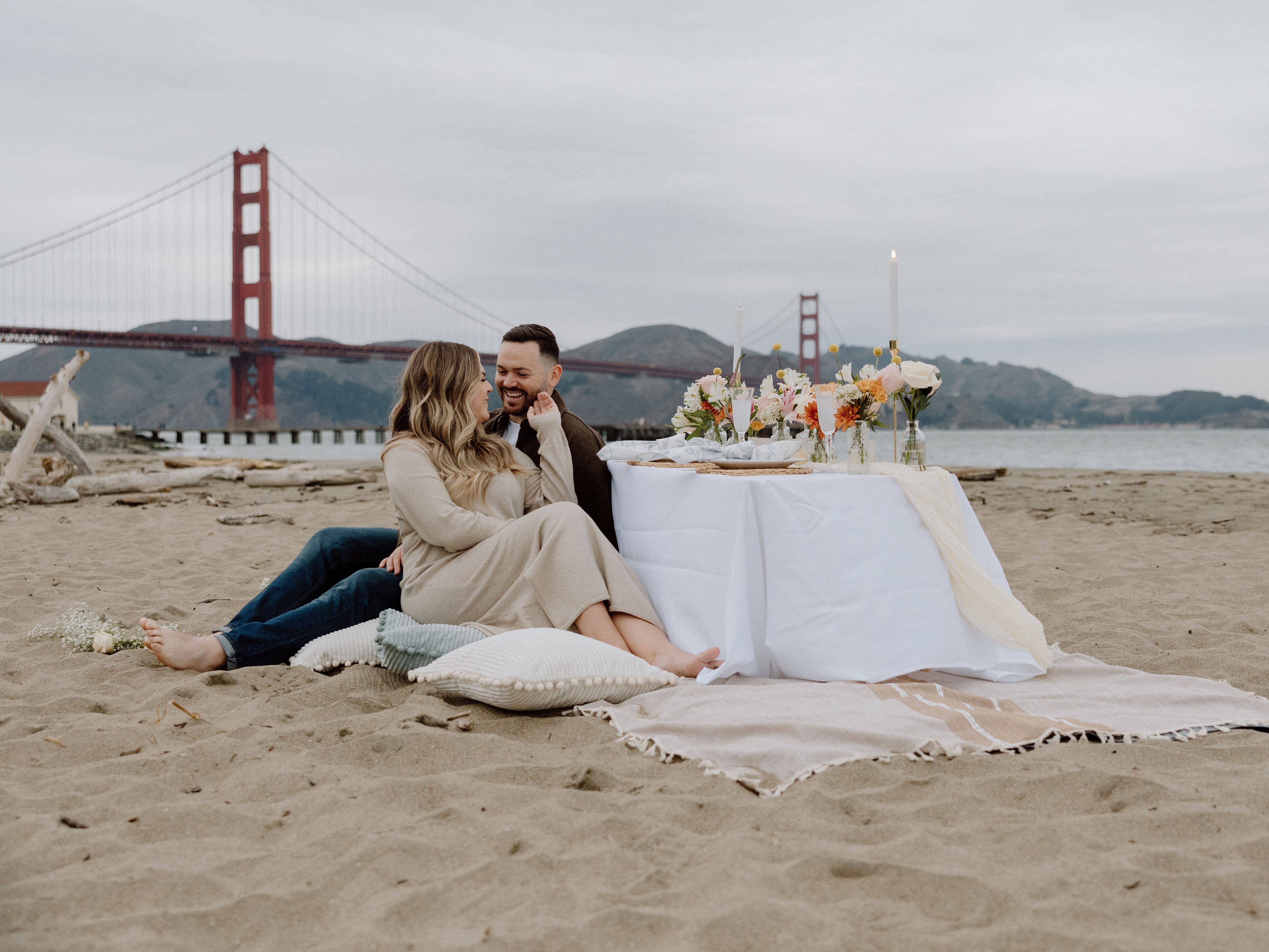 Couple having a picnic on a beach beside the Golden Gate Bridge