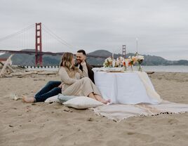 Couple having a picnic on a beach beside the Golden Gate Bridge