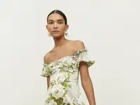Model wears a pale green silk gown with a floral pattern. 
